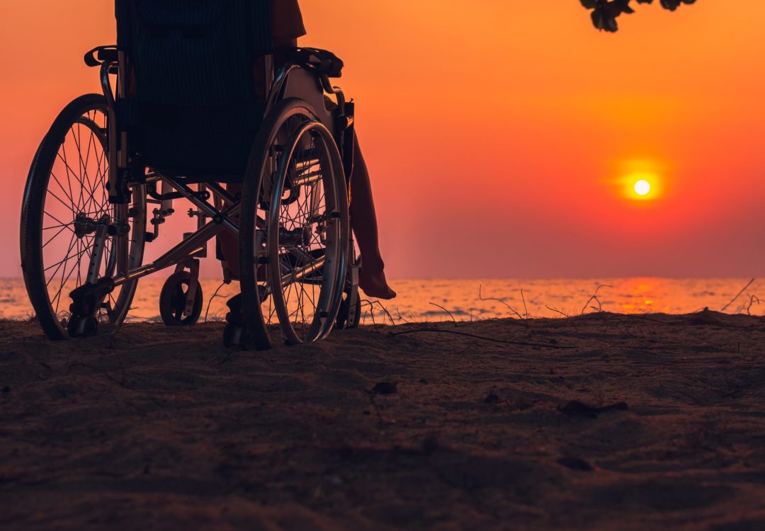 Asian special child on wheelchair on the sea beach with sunset on travel time in holiday family and learning about nature around the sea,Lifestyle in the education age kids,Happy disabled kid concept.